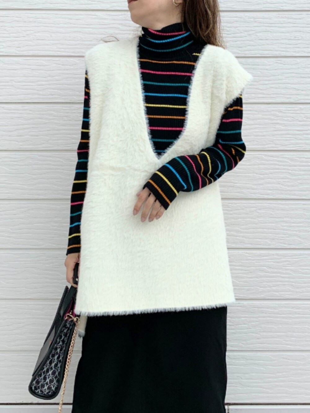 ホワイト系のスニーカー、ブラック系のニット/セーター、ブラック系のショルダーバッグを着用したレディースの秋コーディネートの3枚目の写真