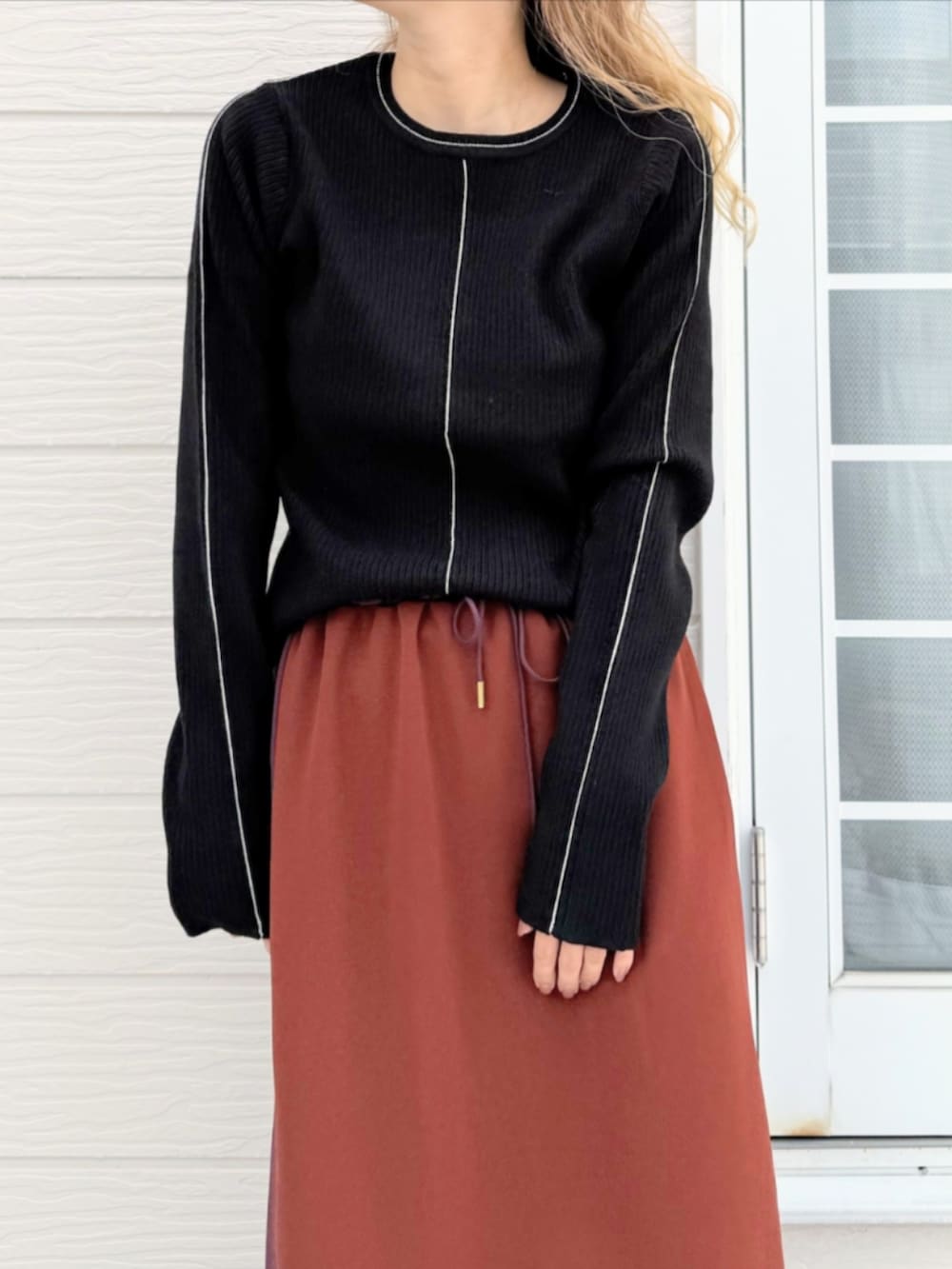 ブラック系のスニーカー、ブラック系のニット/セーター、ブラウン系のスカートを着用したレディースの秋コーディネートの4枚目の写真