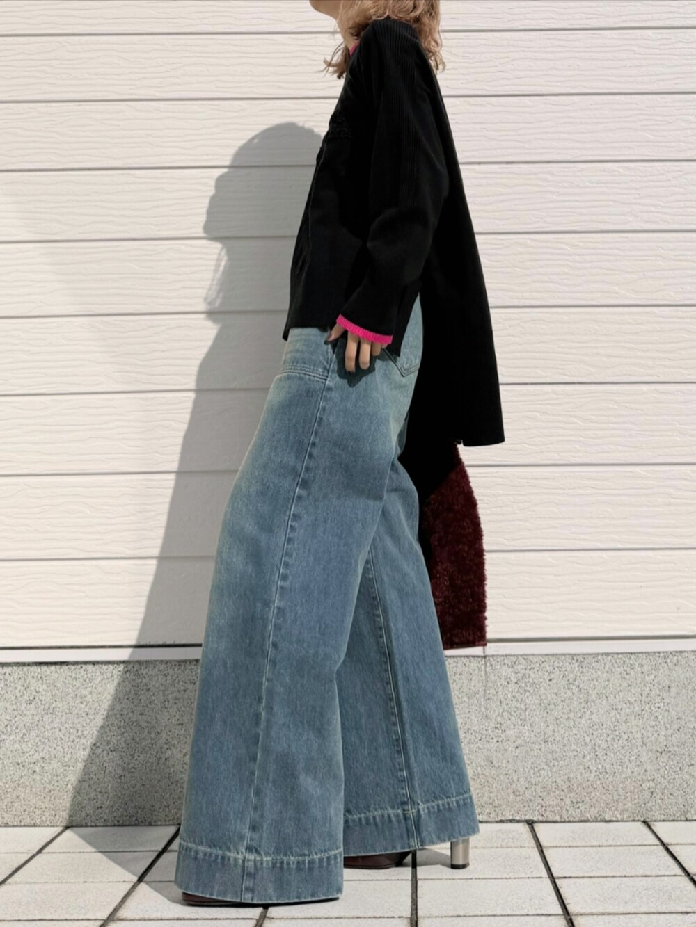 レッド系のトートバッグ、ブルー系のデニムパンツ、ブラック系のニット/セーターを着用したレディースの秋コーディネートの2枚目の写真