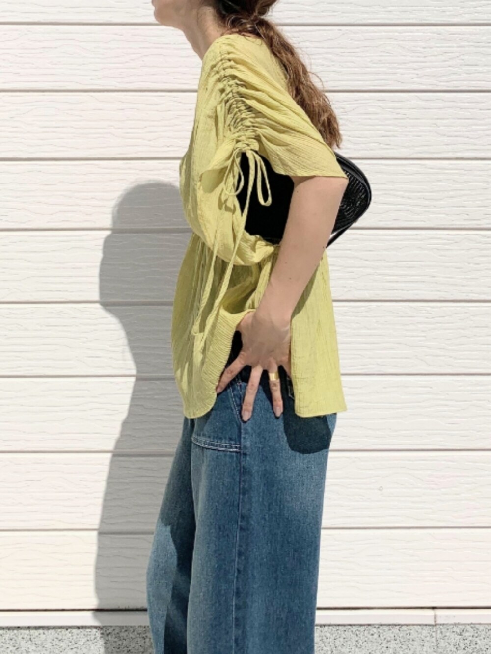 ブラック系のショルダーバッグ、ブラウン系のサンダル、イエロー系のシャツ/ブラウスを着用したレディースの春コーディネートの5枚目の写真