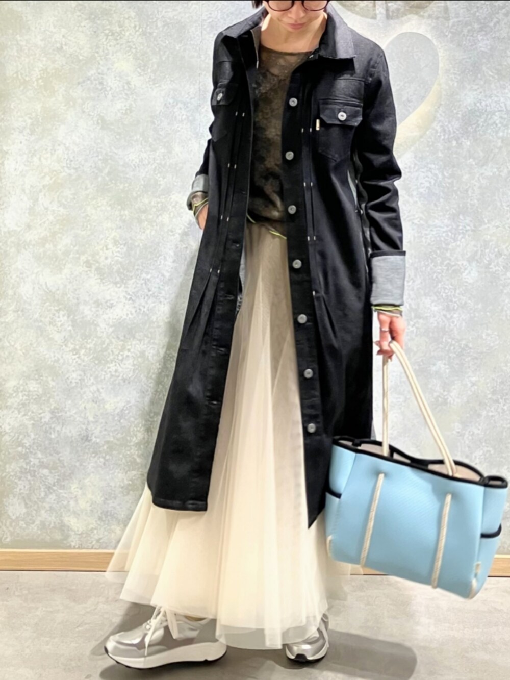 ブルー系のトートバッグ、ゴールド系のスカート、ブラック系のデニムジャケットを着用したレディースの冬コーディネートの2枚目の写真