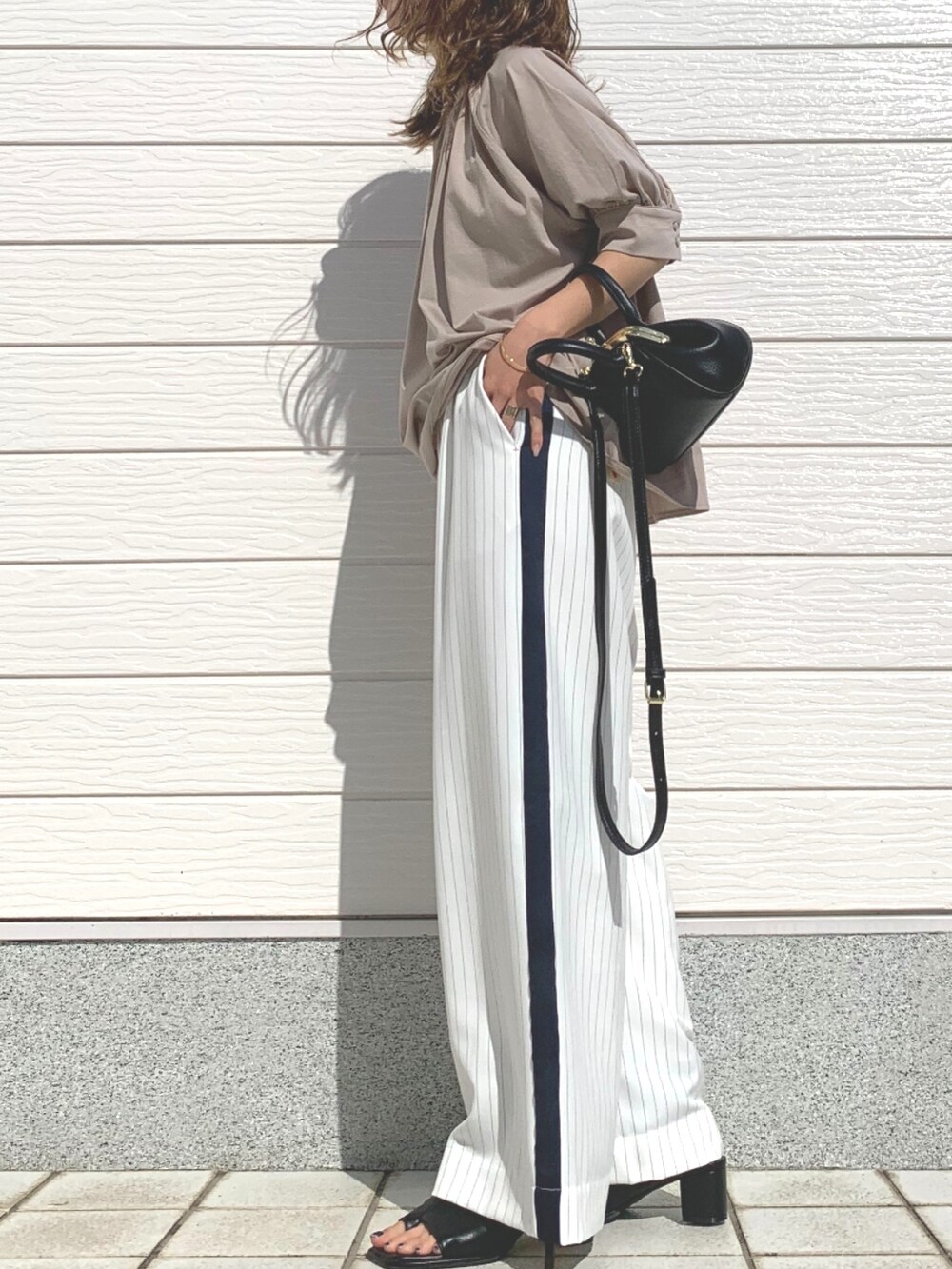 ブラック系のショルダーバッグ、ホワイト系のその他パンツ、ブラック系のサンダルを着用したレディースの春コーディネートの3枚目の写真
