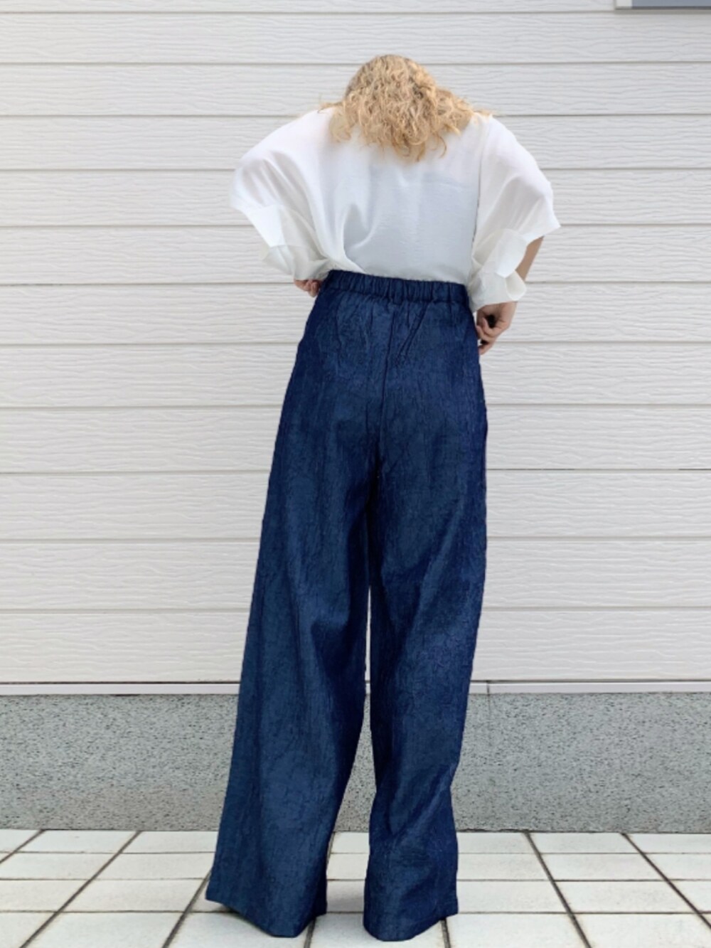 ホワイト系のTシャツ/カットソー、ブラック系のかごバッグ、ブルー系のデニムパンツを着用したレディースの春コーディネートの3枚目の写真