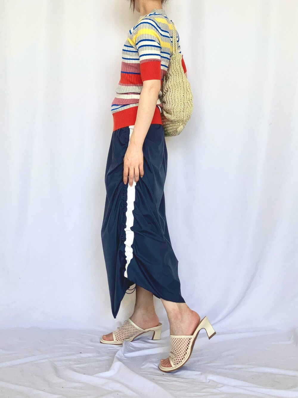 グレー系のニット/セーター、ブルー系のスカート、グレー系のサンダルを着用したレディースの夏コーディネートの2枚目の写真