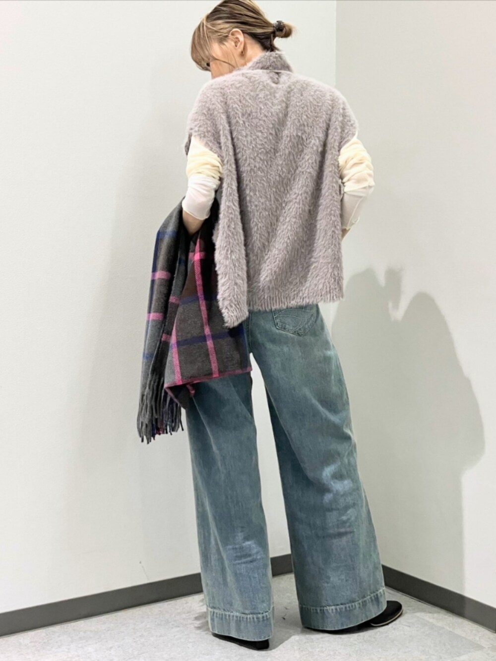 ブルー系のデニムパンツ、グレー系のベスト、ベージュ系のTシャツ/カットソーを着用したレディースの秋コーディネートの3枚目の写真