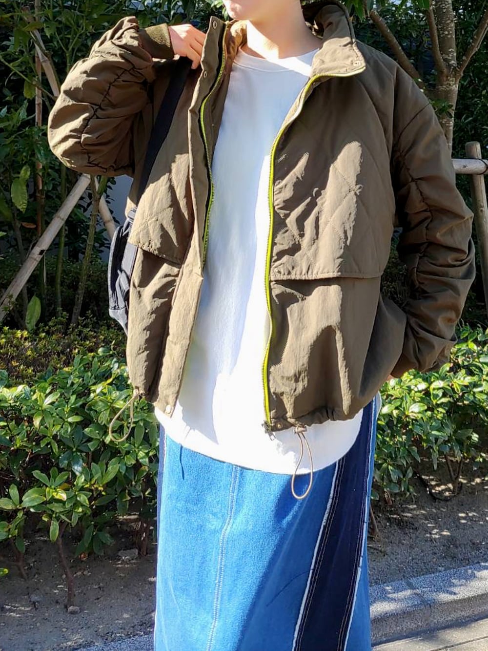 グリーン系のミリタリージャケット、ブラック系のバックパック/リュック、ホワイト系のTシャツ/カットソーを着用したレディースの秋コーディネートの2枚目の写真