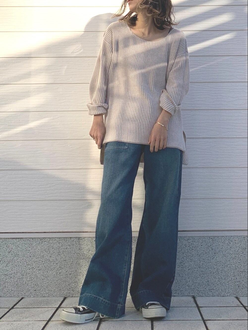 ベージュ系のニット/セーター、ブラック系のスニーカー、ブルー系のデニムパンツを着用したレディースの冬コーディネートの2枚目の写真