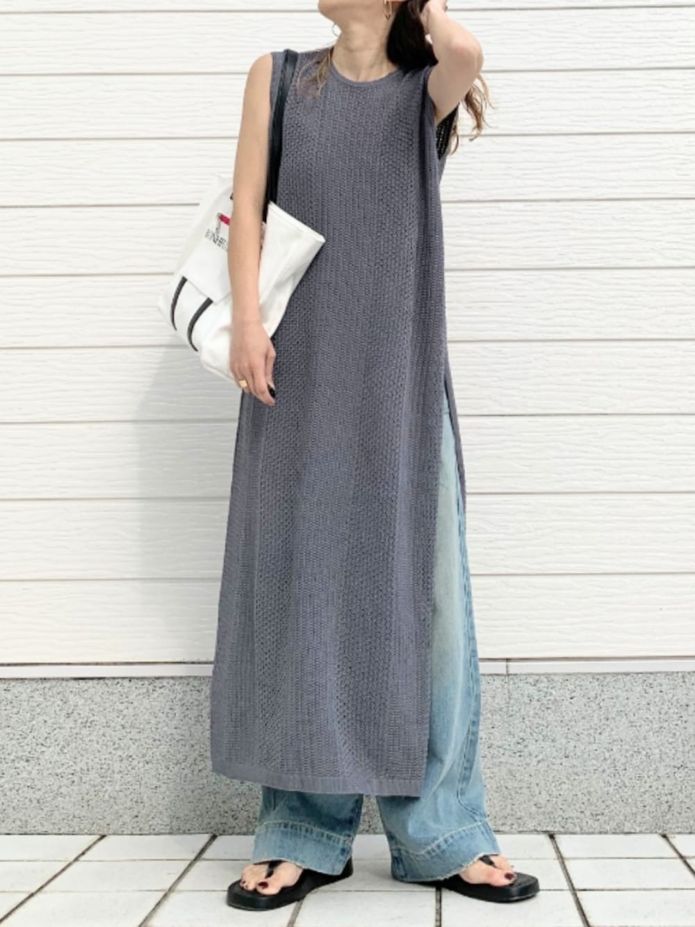 ホワイト系のトートバッグ、ブルー系のデニムパンツ、グレー系のワンピースを着用したレディースの春コーディネートの2枚目の写真