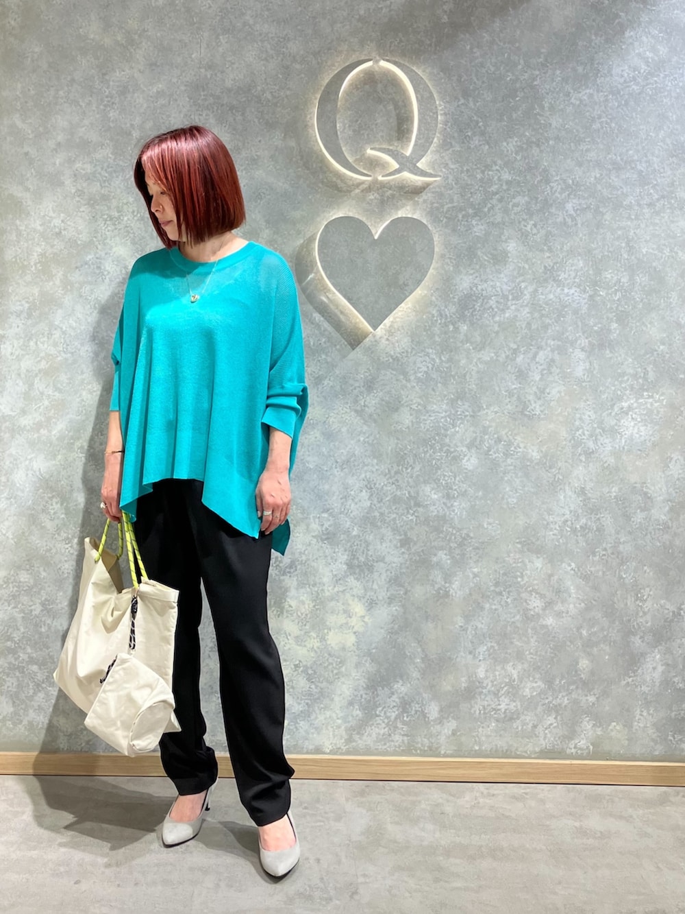 グリーン系のニット/セーター、ブラック系のその他パンツ、ホワイト系のトートバッグを着用したレディースの春コーディネートの2枚目の写真