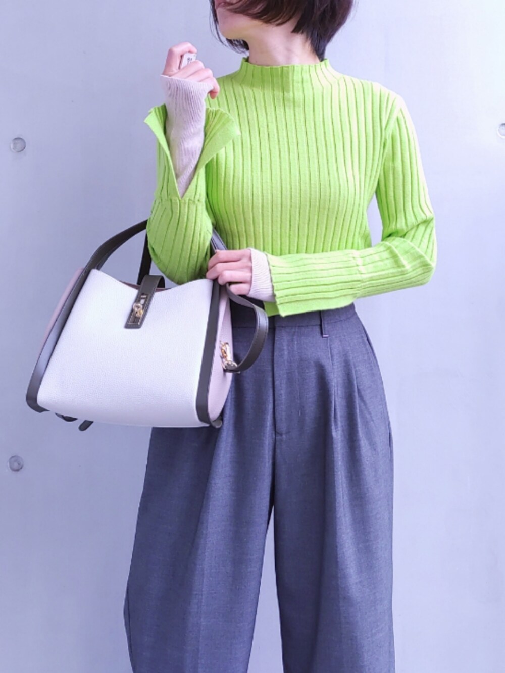 グレー系のスラックス、ホワイト系のトートバッグ、グリーン系のニット/セーターを着用したレディースの冬コーディネートの3枚目の写真
