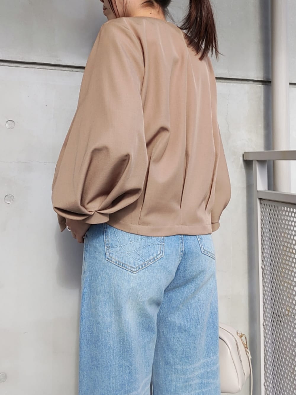 ブルー系のデニムパンツ、ホワイト系のスニーカー、ホワイト系のボストンバッグを着用したレディースの冬コーディネートの4枚目の写真