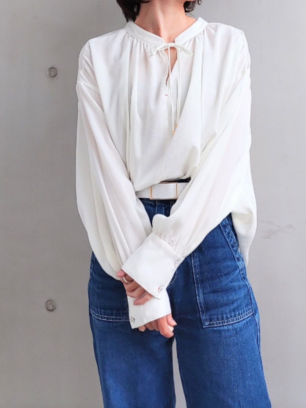 ブルー系のデニムパンツ、ホワイト系のスニーカー、ブラック系のニット/セーターを着用したレディースの秋コーディネートの3枚目の写真