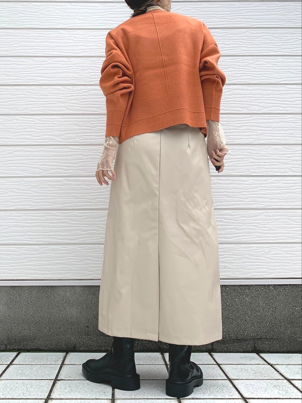 オレンジ系のニット/セーター、ベージュ系のTシャツ/カットソー、ベージュ系のスカートを着用したレディースの秋コーディネートの2枚目の写真