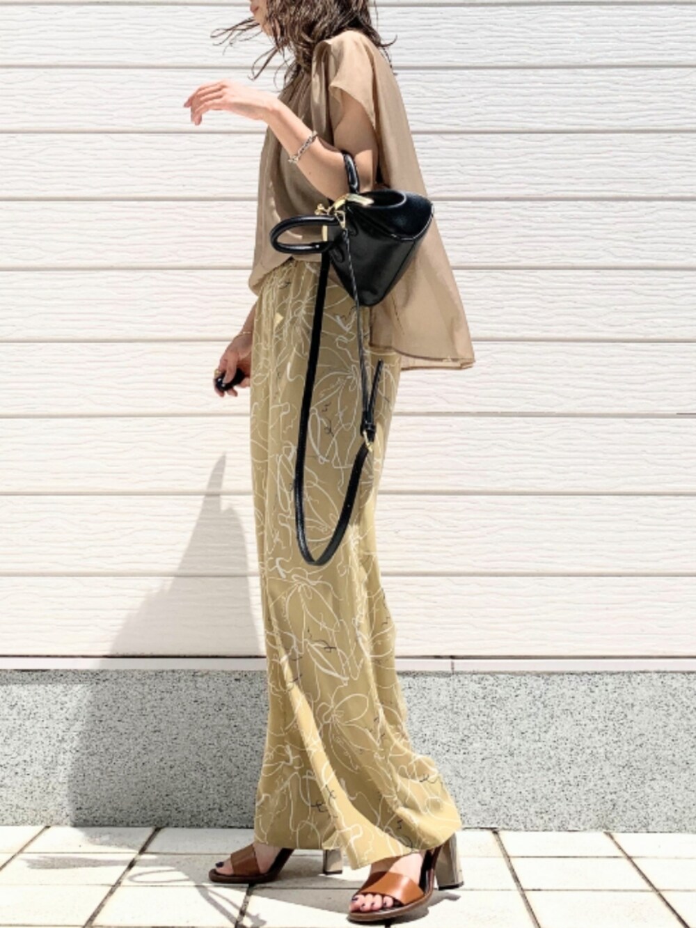 ブラウン系のサンダル、ベージュ系のその他パンツ、ブラック系のショルダーバッグを着用したレディースの春コーディネートの2枚目の写真