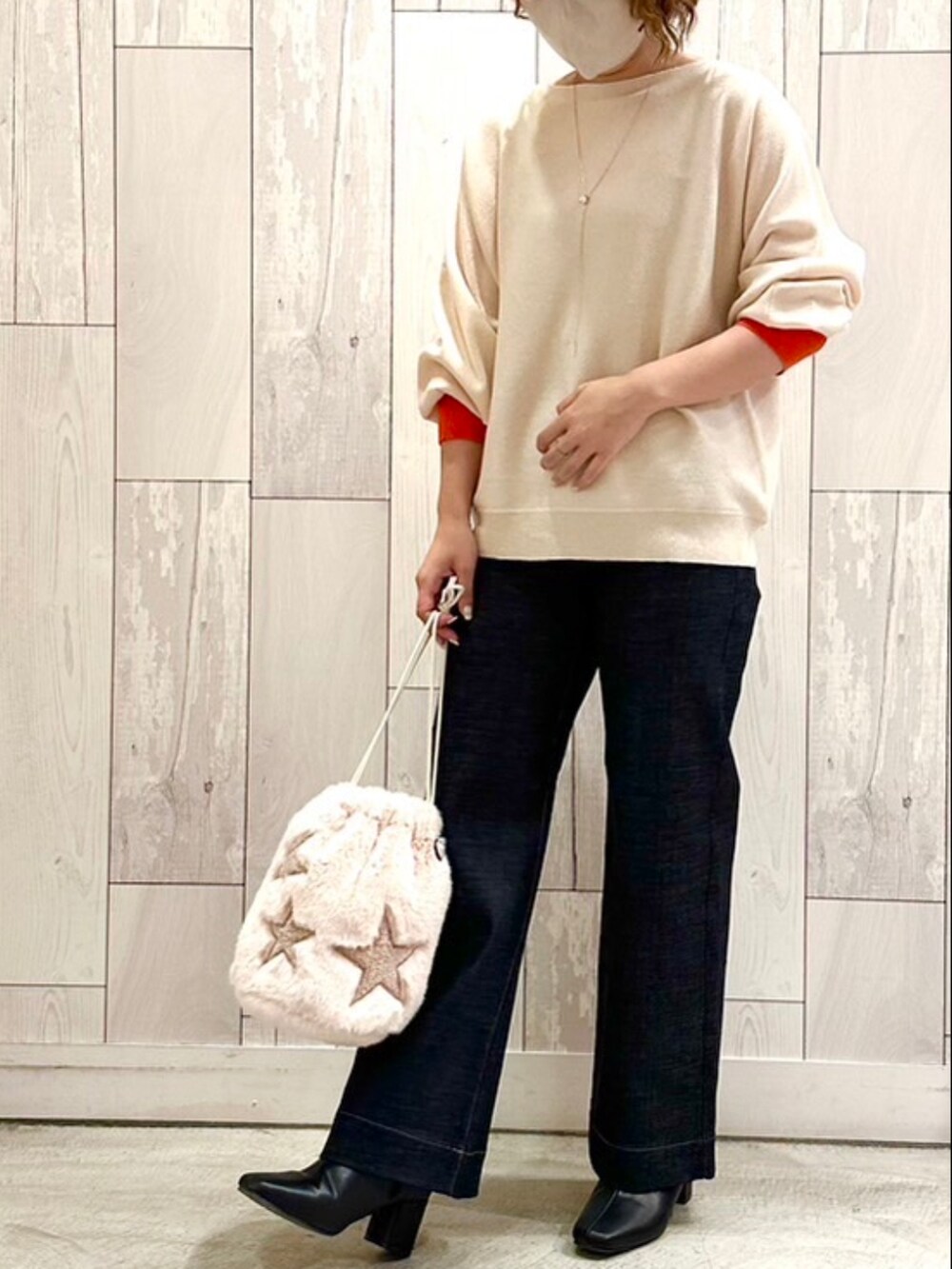 ブルー系のデニムパンツ、ベージュ系のショルダーバッグ、ホワイト系のニット/セーターを着用したレディースの秋コーディネートの2枚目の写真