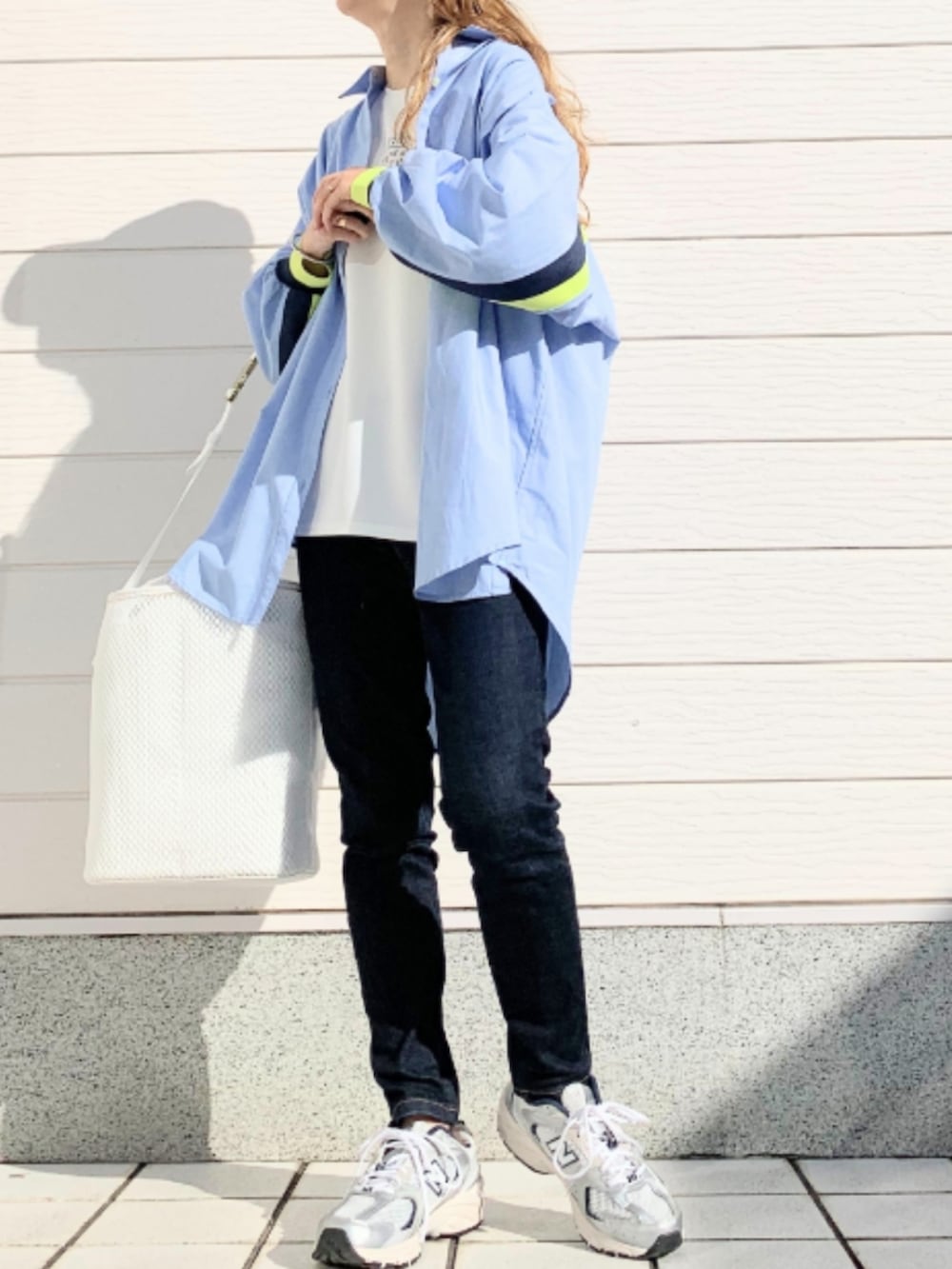 ブルー系のデニムパンツ、シルバー系のスニーカー、ホワイト系のショルダーバッグを着用したレディースの冬コーディネートの3枚目の写真