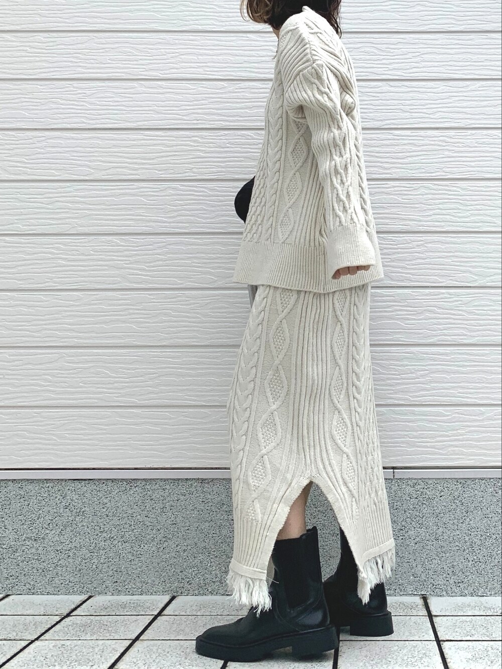 シルバー系のショルダーバッグ、ホワイト系のスカート、ホワイト系のニット/セーターを着用したレディースの冬コーディネートの2枚目の写真