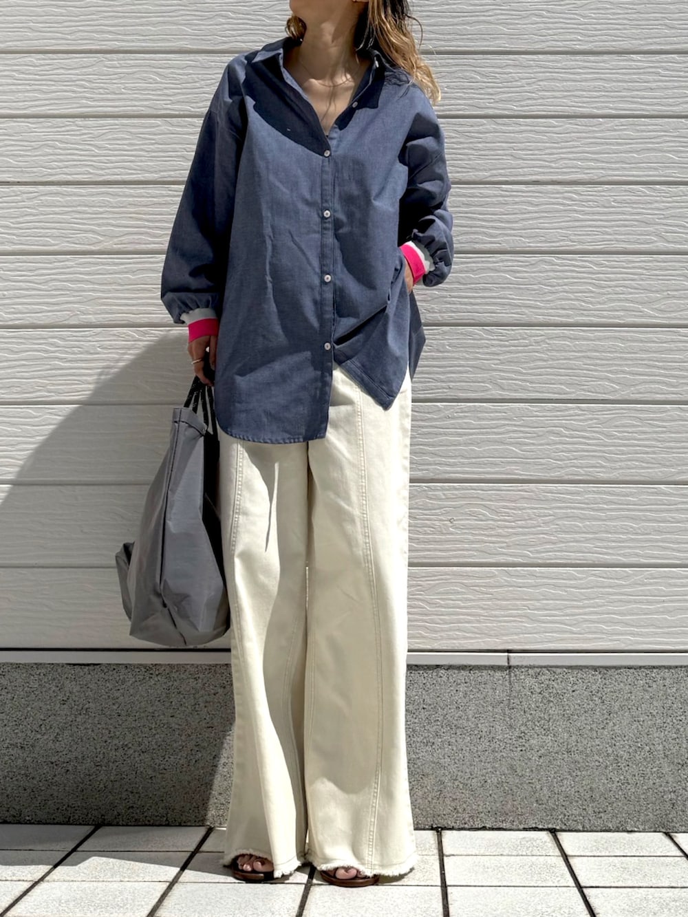 ホワイト系のデニムパンツ、グレー系のトートバッグ、ブルー系のシャツ/ブラウスを着用したレディースの春コーディネートの2枚目の写真