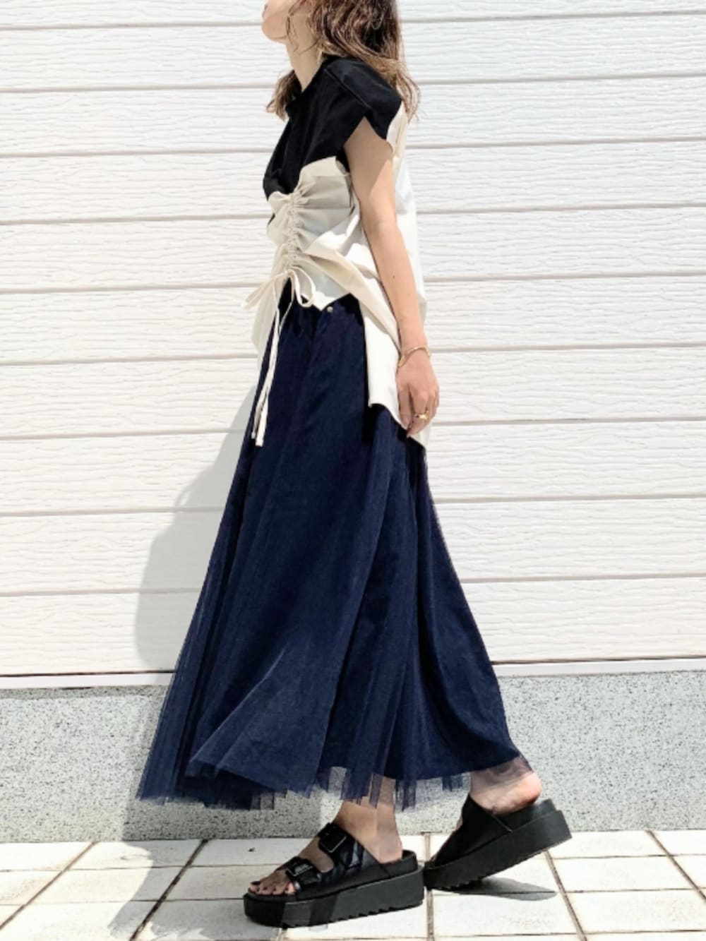 パープル系のショルダーバッグ、ブラック系のサンダル、ブルー系のスカートを着用したレディースの春コーディネートの2枚目の写真