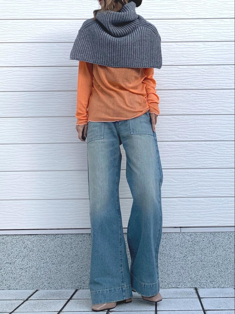 オレンジ系のTシャツ/カットソー、ブルー系のデニムパンツ、グレー系のネックウォーマー/スヌードを着用したレディースの冬コーディネートの2枚目の写真