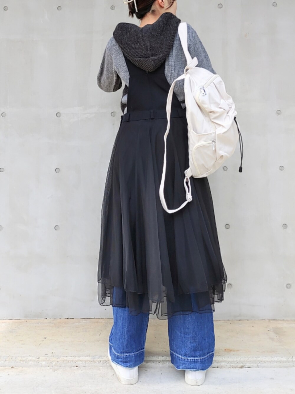 ホワイト系のバックパック/リュック、グレー系のニット/セーター、ブラック系のジャンパースカートを着用したレディースの秋コーディネートの2枚目の写真
