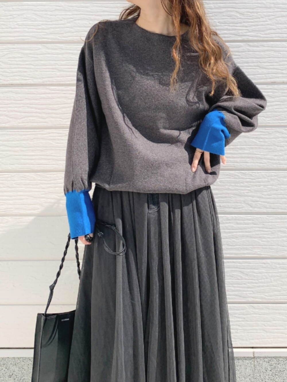 ブラック系のスカート、グレー系のニット/セーターを着用したレディースの秋コーディネートの4枚目の写真