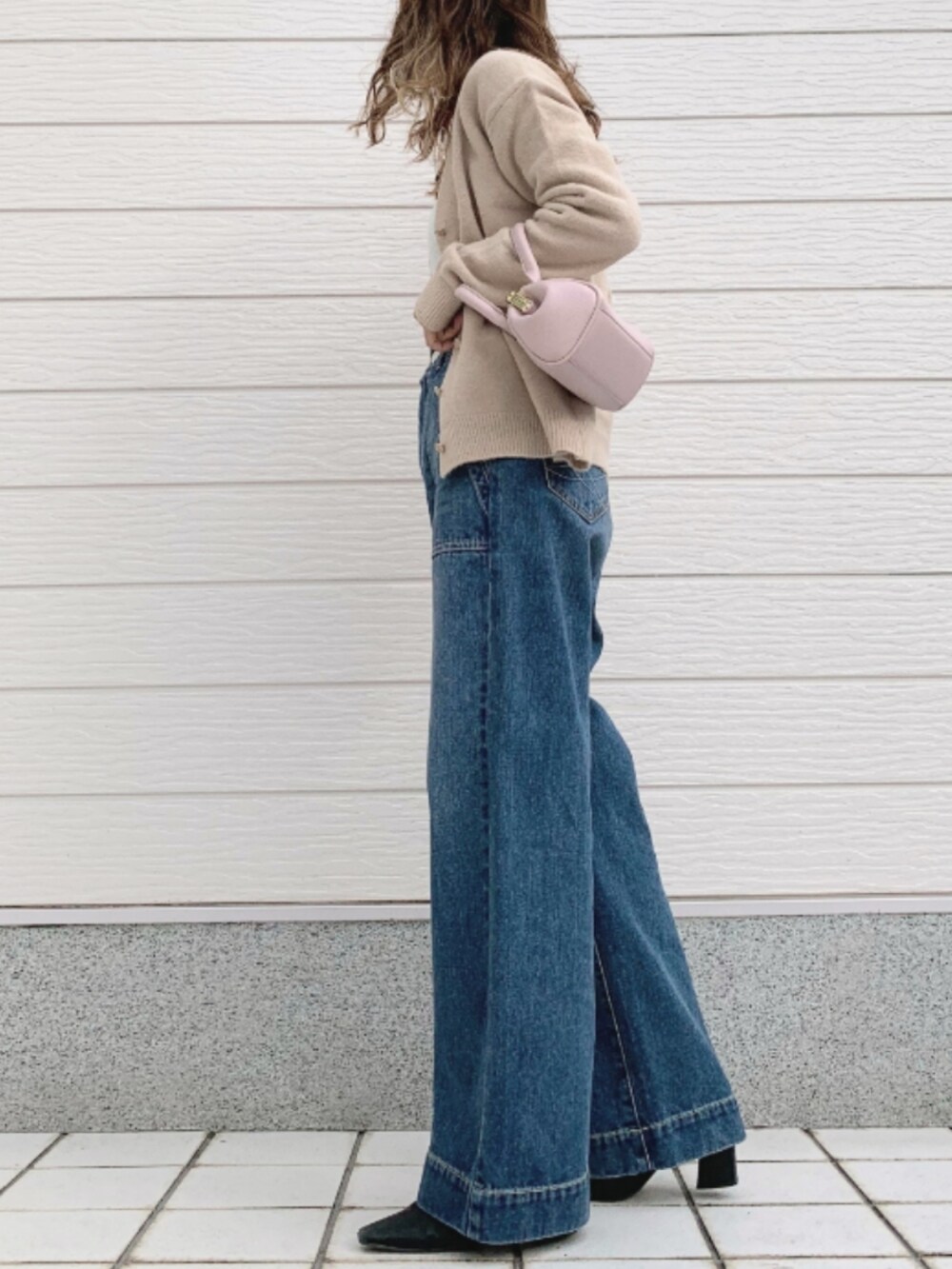 ブルー系のデニムパンツ、ピンク系のショルダーバッグ、ホワイト系のカーディガン/ボレロを着用したレディースの秋コーディネートの2枚目の写真