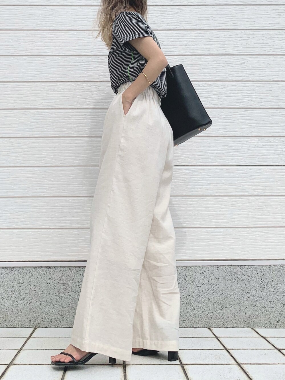 ブラック系のTシャツ/カットソー、ホワイト系のその他パンツ、ブラック系のトートバッグを着用したレディースの春コーディネートの2枚目の写真