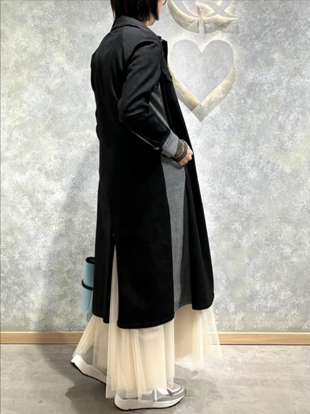 ブルー系のトートバッグ、ゴールド系のスカート、ブラック系のデニムジャケットを着用したレディースの冬コーディネートの3枚目の写真