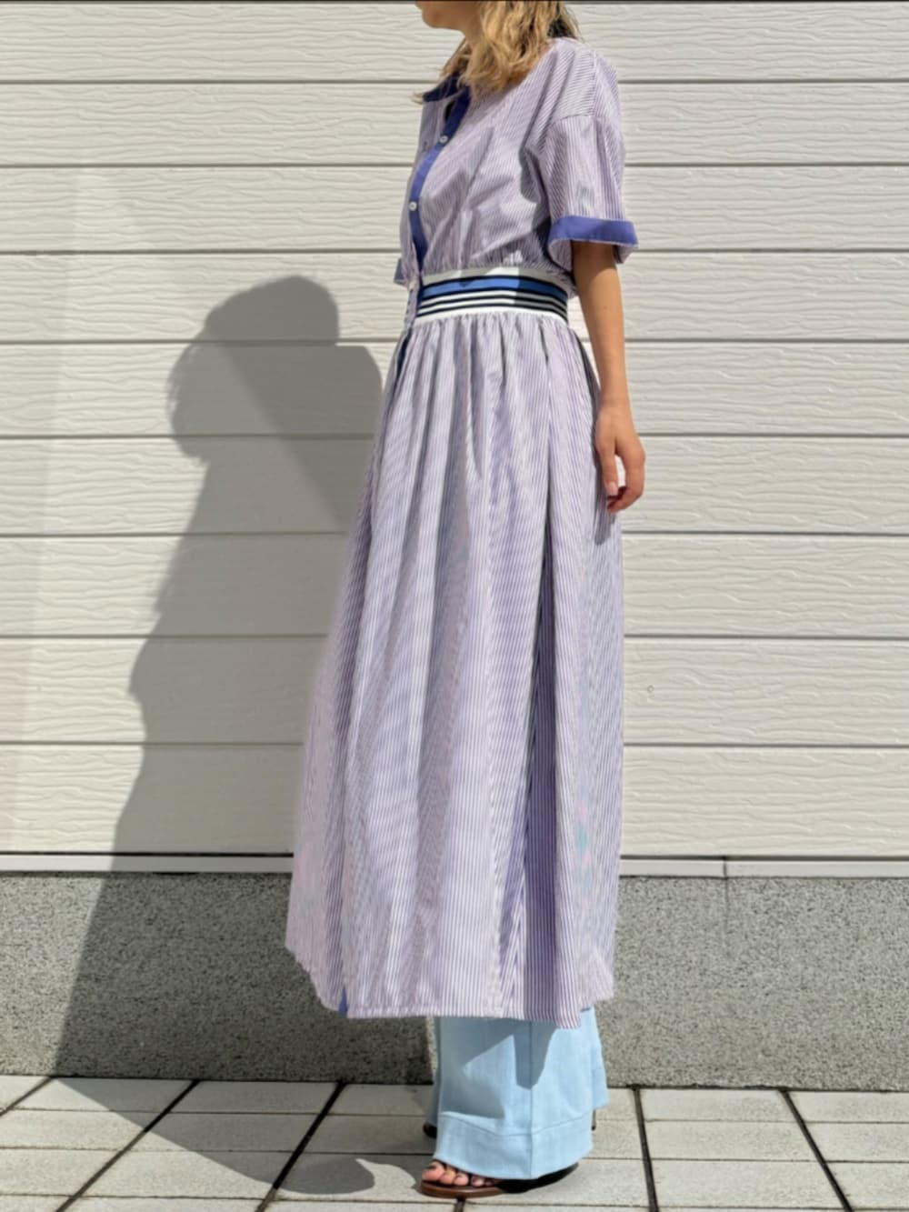 ブルー系のデニムパンツ、シルバー系のトートバッグ、パープル系のワンピースを着用したレディースの春コーディネートの2枚目の写真