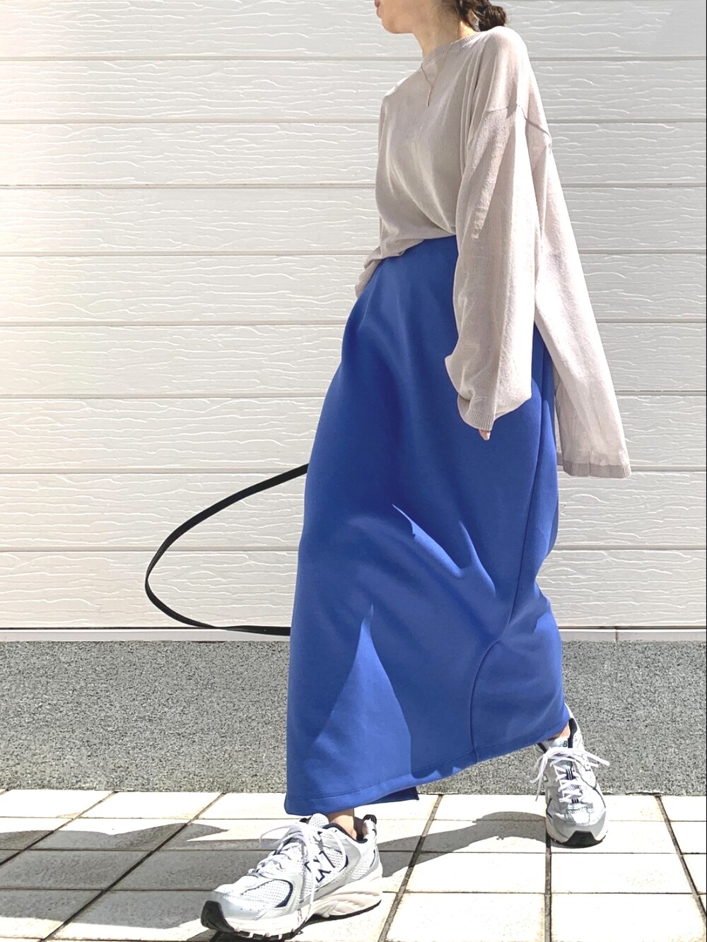 ブルー系のスカート、ブラック系のショルダーバッグ、ベージュ系のニット/セーターを着用したレディースの春コーディネートの2枚目の写真