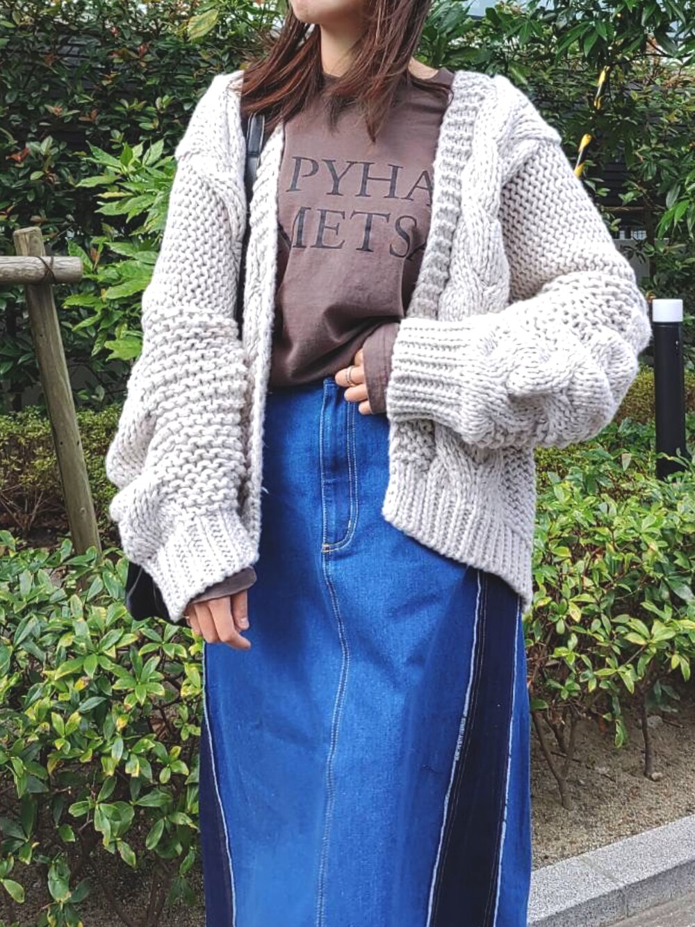 グレー系のTシャツ/カットソー、ブルー系のデニムスカート、ホワイト系のスニーカーを着用したレディースの秋コーディネートの3枚目の写真