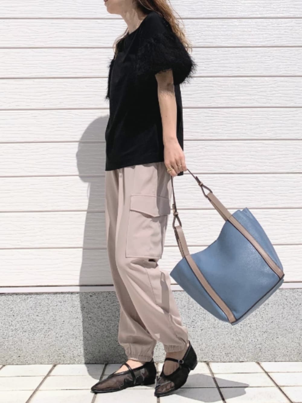 ベージュ系のカーゴパンツ、ブラック系のTシャツ/カットソー、ブルー系のトートバッグを着用したレディースの春コーディネートの2枚目の写真