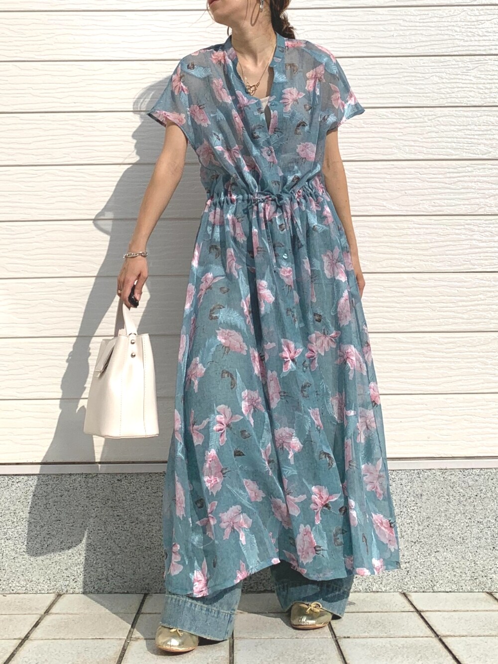 ブルー系のデニムパンツ、ベージュ系のキャミソール、ホワイト系のハンドバッグを着用したレディースの春コーディネートの3枚目の写真
