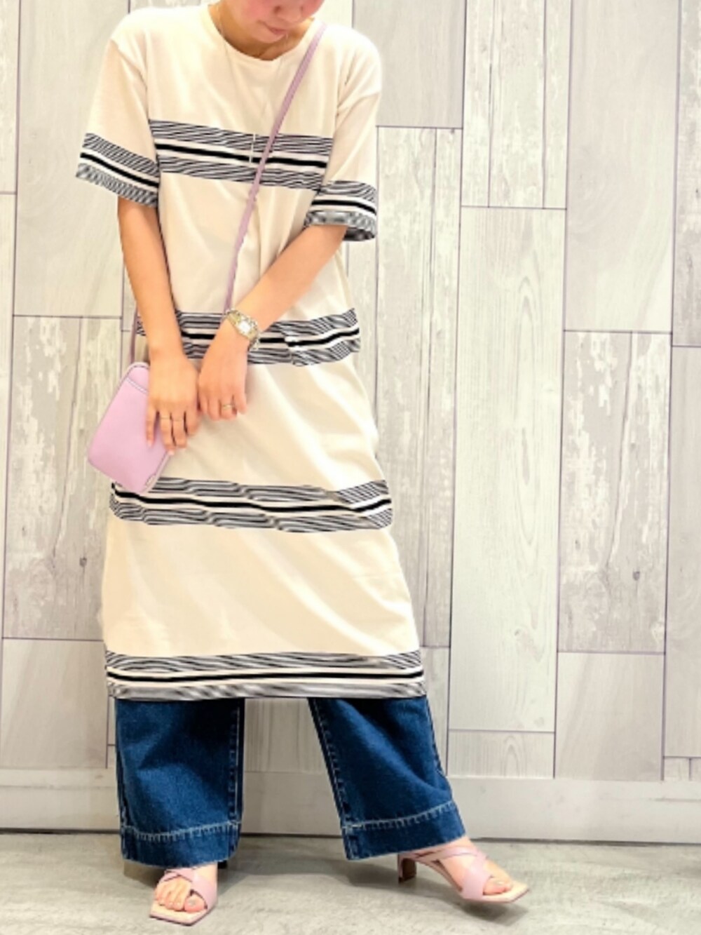 パープル系のショルダーバッグ、ブルー系のデニムパンツ、パープル系のサンダルを着用したレディースの春コーディネートの2枚目の写真