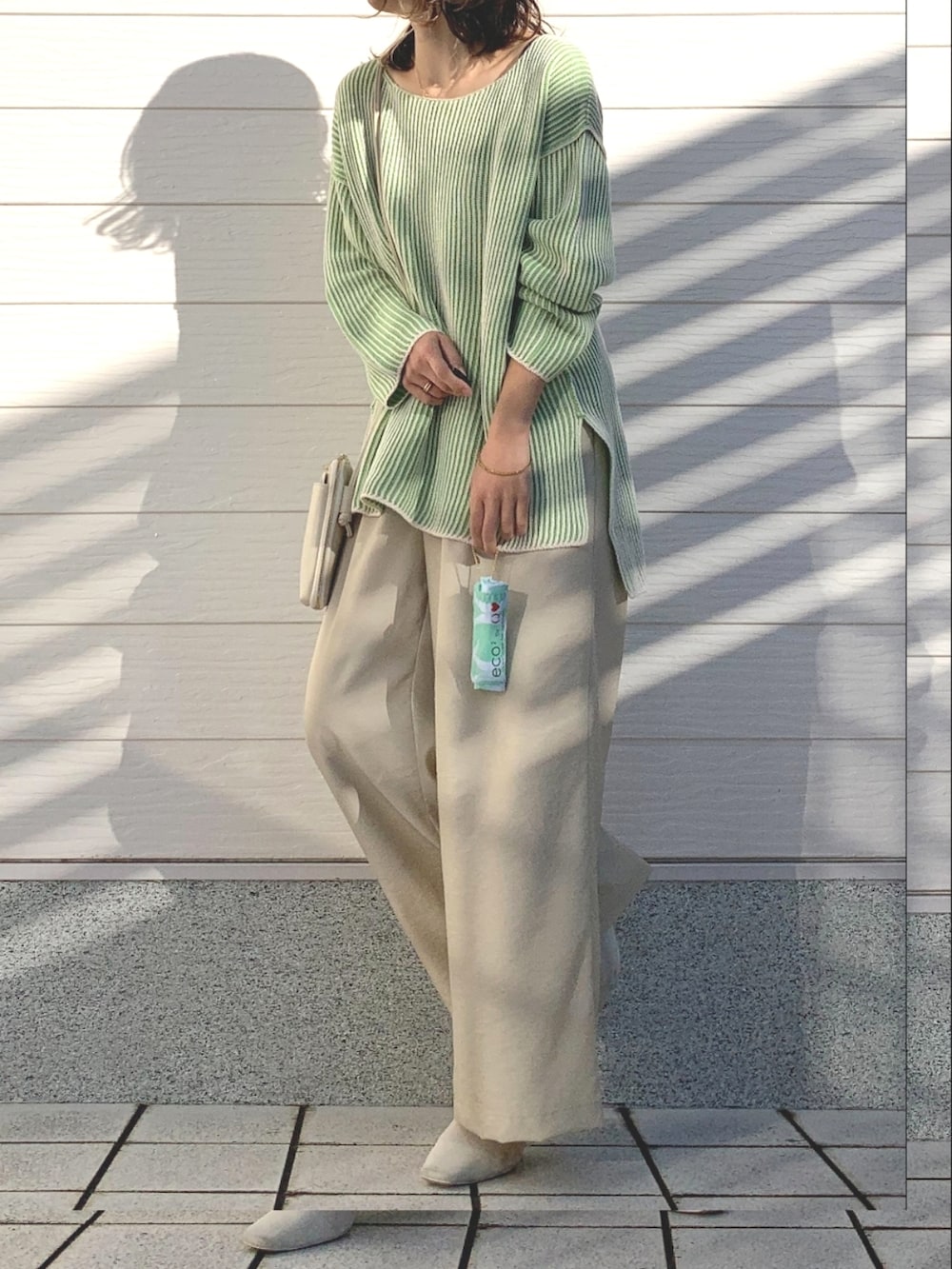 ベージュ系のその他パンツ、グリーン系のニット/セーター、ホワイト系のショルダーバッグを着用したレディースの冬コーディネートの2枚目の写真