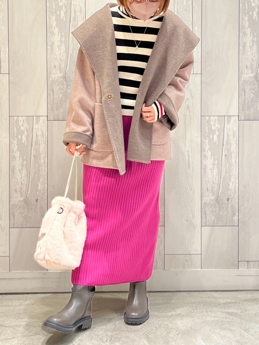 ベージュ系のショルダーバッグ、ピンク系のスカート、グレー系のブーツを着用したレディースの冬コーディネートの2枚目の写真