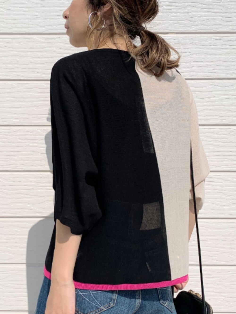 ブルー系のデニムパンツ、ブラック系のショルダーバッグ、ブラック系のニット/セーターを着用したレディースの春コーディネートの4枚目の写真