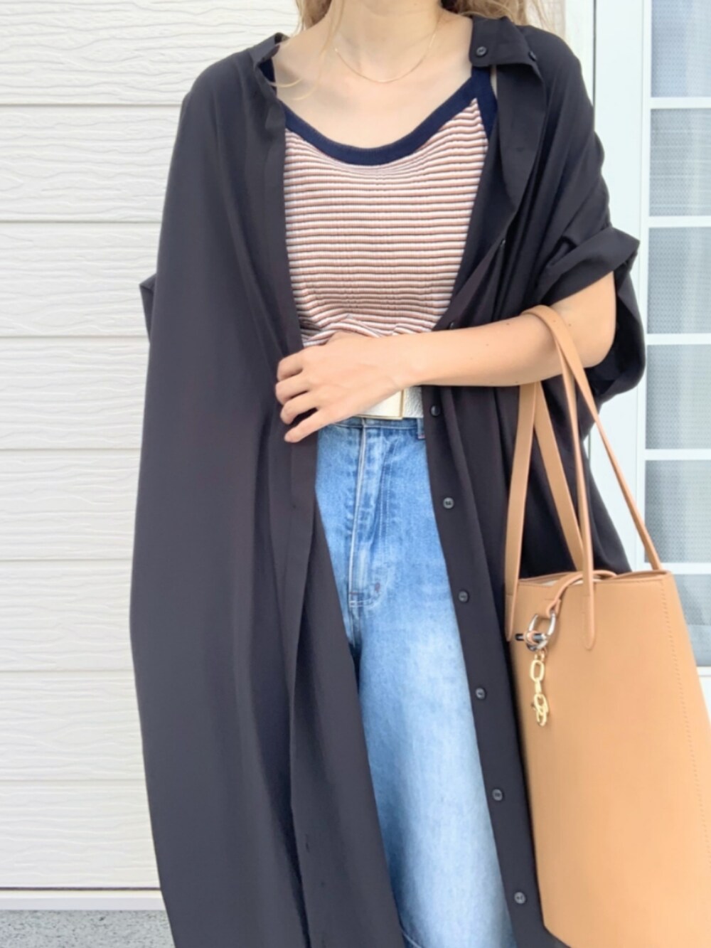 グレー系のトートバッグ、ブルー系のデニムパンツ、ブラック系のシャツワンピースを着用したレディースの夏コーディネートの5枚目の写真