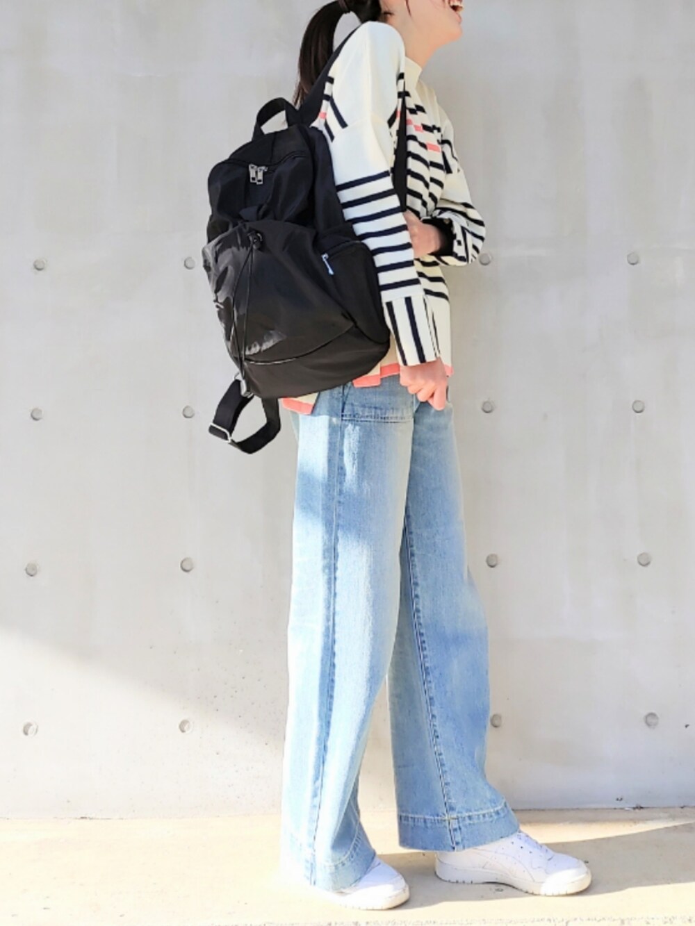 ブルー系のデニムパンツ、ホワイト系のスニーカー、ブラック系のバックパック/リュックを着用したレディースの冬コーディネートの3枚目の写真