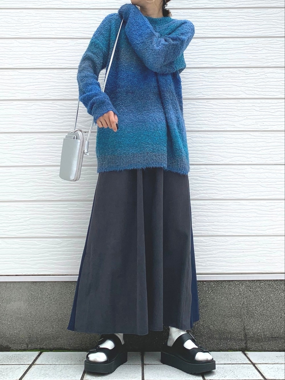 ブルー系のニット/セーター、シルバー系のショルダーバッグ、グレー系のスカートを着用したレディースの秋コーディネートの2枚目の写真