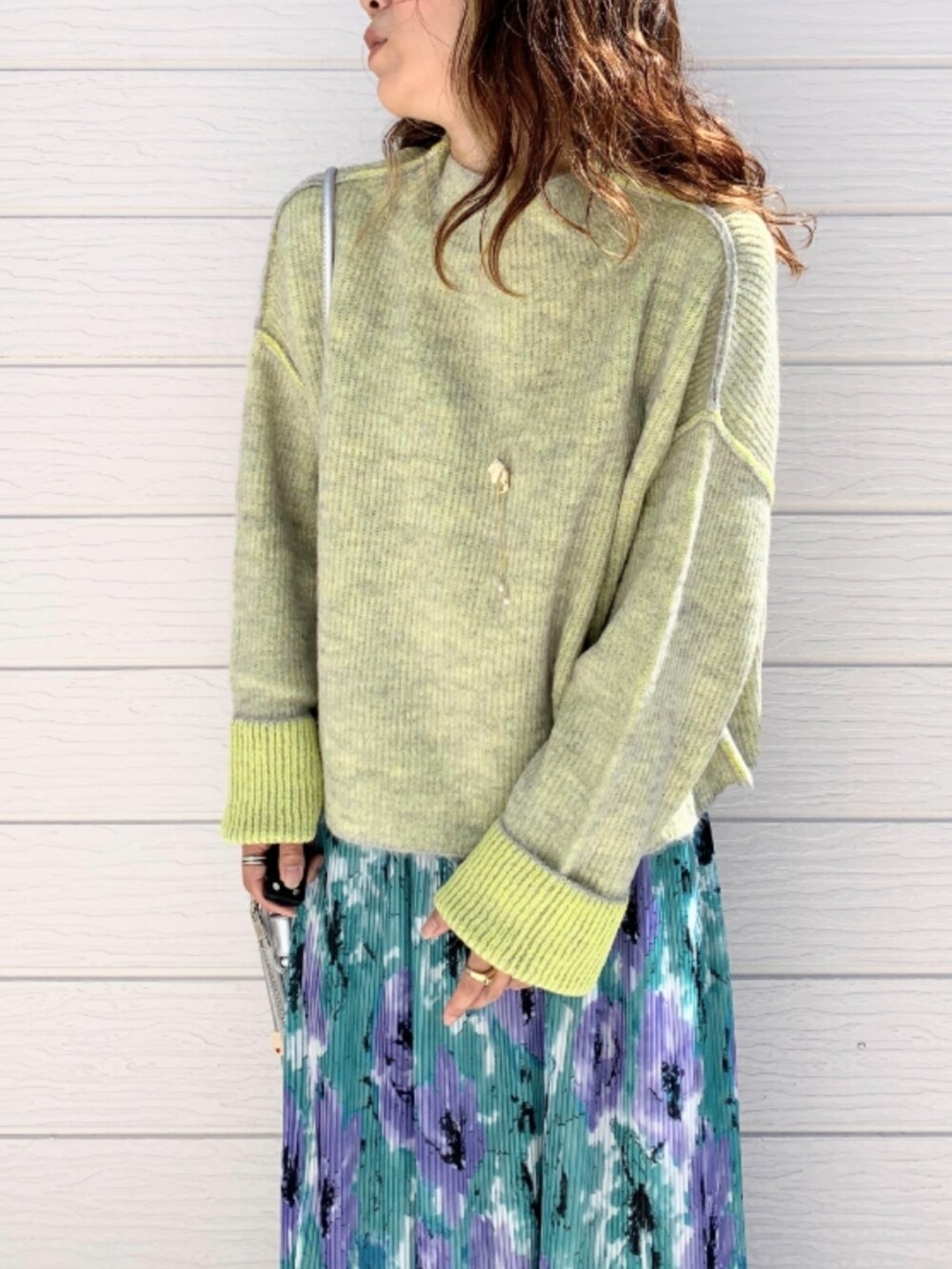 グリーン系のスカート、ホワイト系のスニーカー、シルバー系のショルダーバッグを着用したレディースの秋コーディネートの3枚目の写真