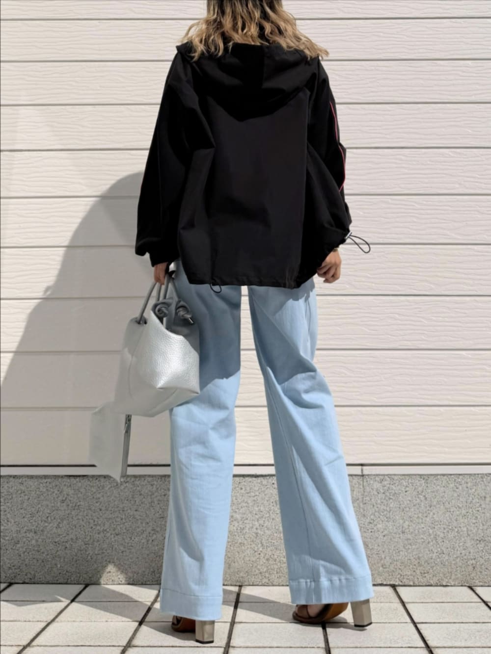ブルー系のデニムパンツ、ブラック系のパーカー、シルバー系のトートバッグを着用したレディースの春コーディネートの3枚目の写真