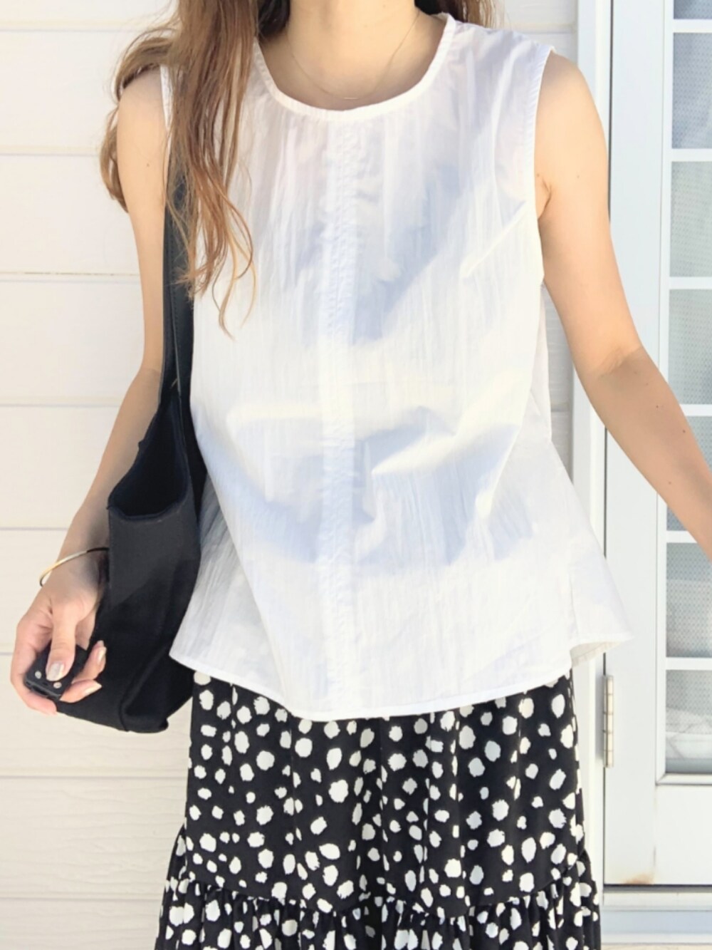 ブラック系のスカート、ホワイト系のトートバッグ、ホワイト系のシャツ/ブラウスを着用したレディースの夏コーディネートの4枚目の写真