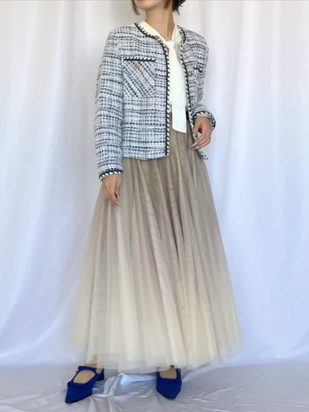 ホワイト系のシャツ/ブラウス、ゴールド系のスカート、ブルー系のパンプスを着用したレディースの冬コーディネートの2枚目の写真