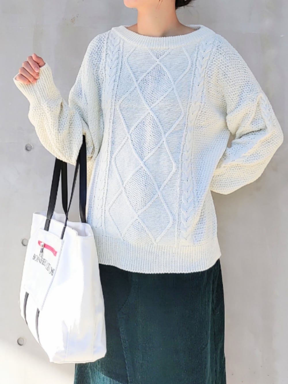 ホワイト系のトートバッグ、ブラック系のスニーカー、ホワイト系のニット/セーターを着用したレディースの冬コーディネートの3枚目の写真