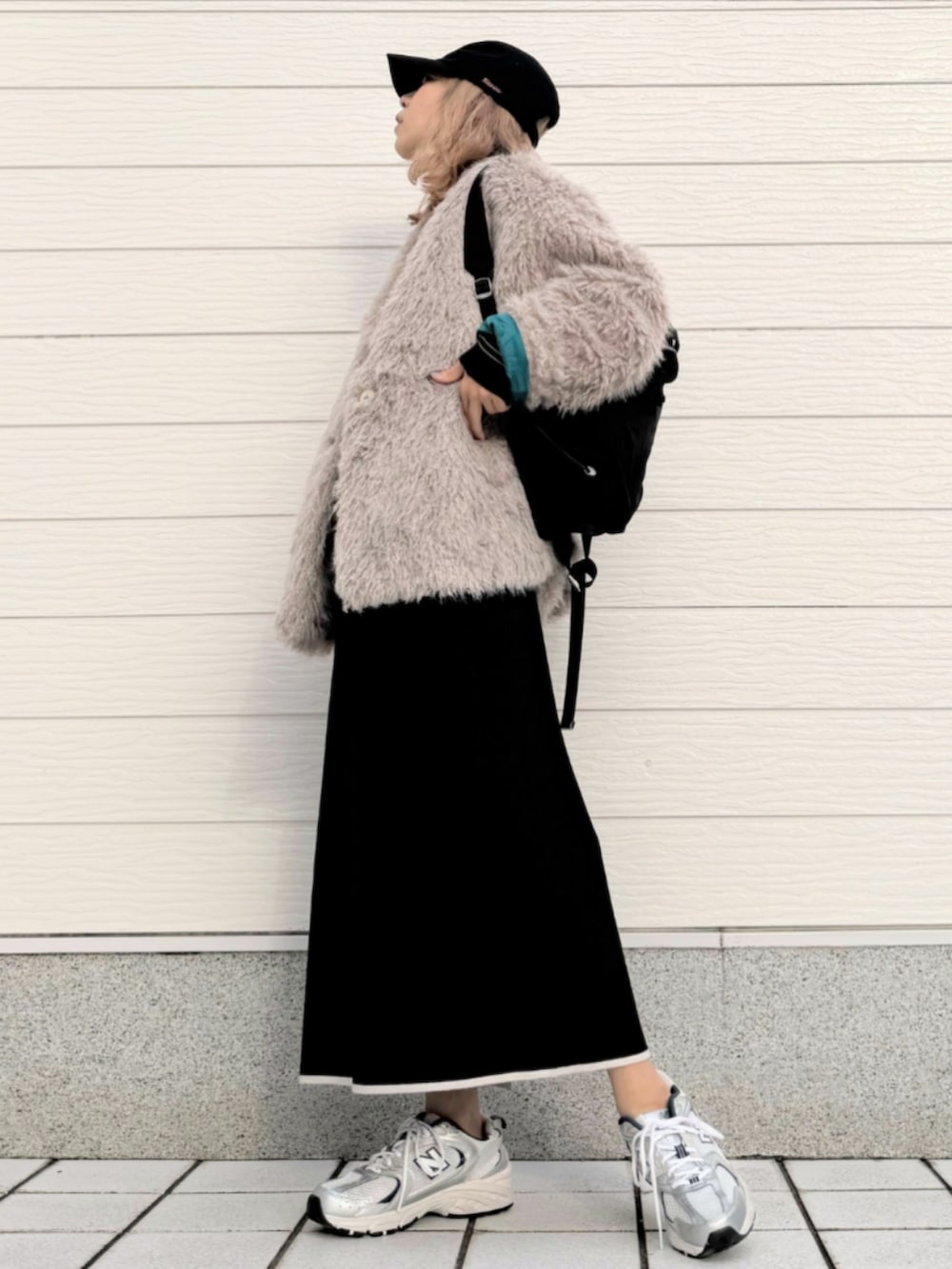 シルバー系のスニーカー、ブラック系のワンピース、ブラック系のバックパック/リュックを着用したレディースの秋コーディネートの2枚目の写真