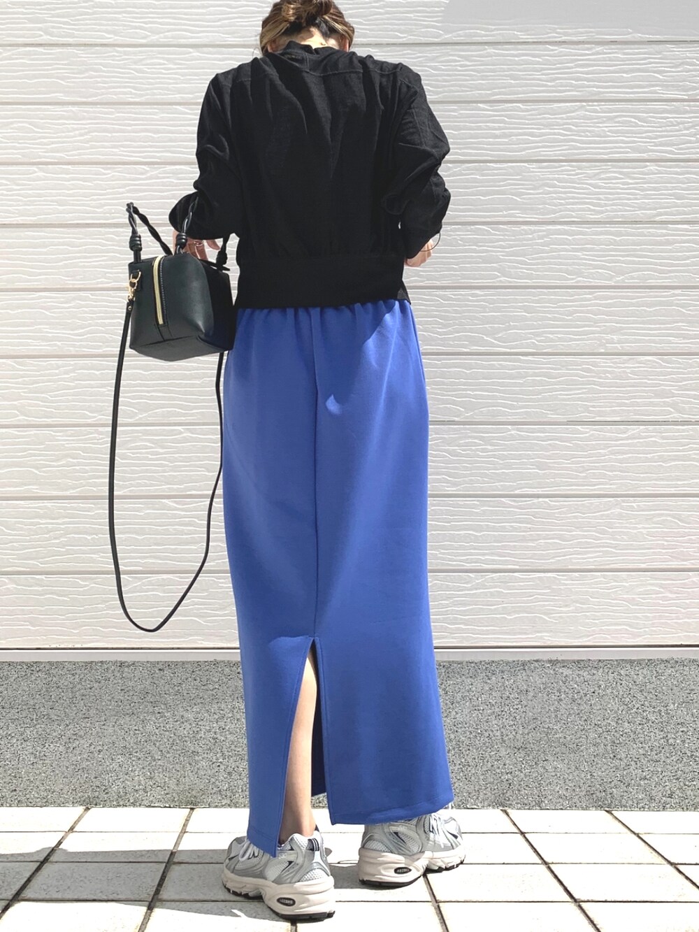 シルバー系のスニーカー、ブルー系のスカート、ブラック系のハンドバッグを着用したレディースの春コーディネートの3枚目の写真