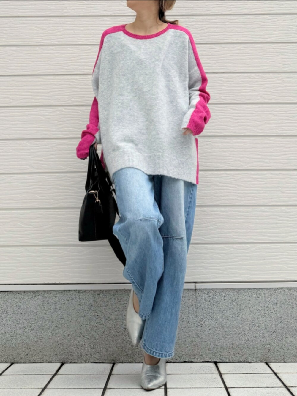 ブルー系のデニムパンツ、ブラック系のトートバッグ、グレー系のニット/セーターを着用したレディースの冬コーディネートの2枚目の写真