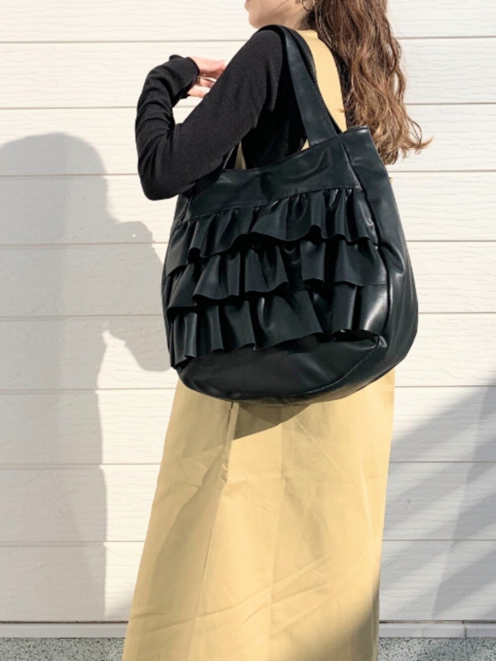 ベージュ系のジャンパースカート、ブラック系のトートバッグを着用したレディースの冬コーディネートの5枚目の写真